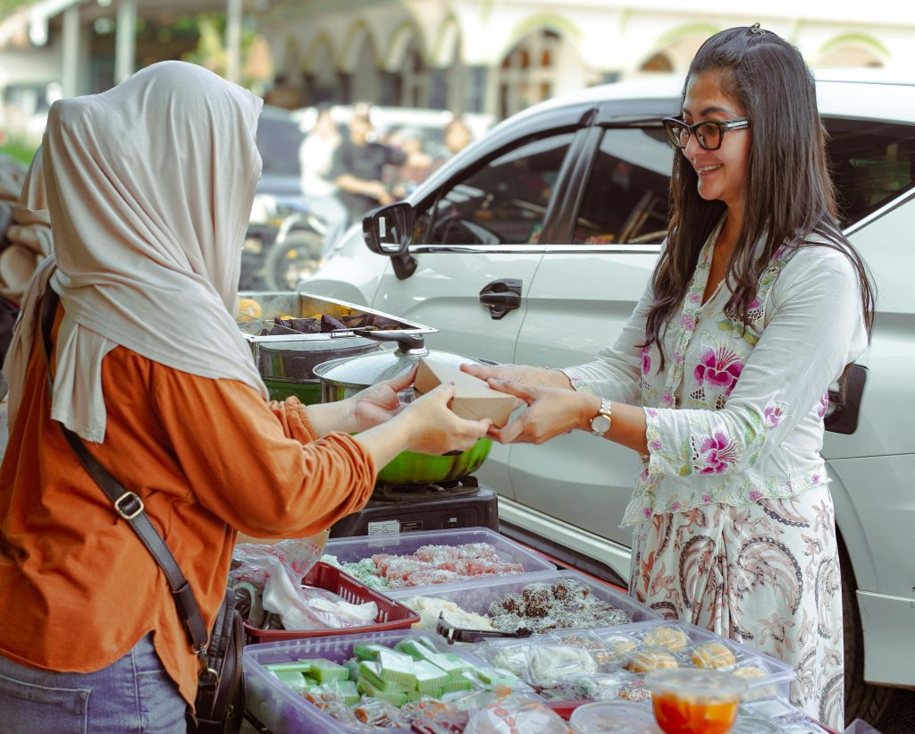 Two women exchanging food at a street market in West Java, Indonesia.